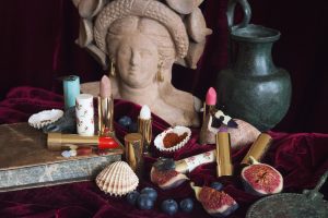 A picture of lipticks and other cosmetics around a marble bust