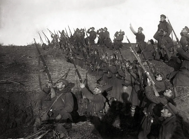 Bulgarian soldiers in a World War I trench raising their rifles during combat.
