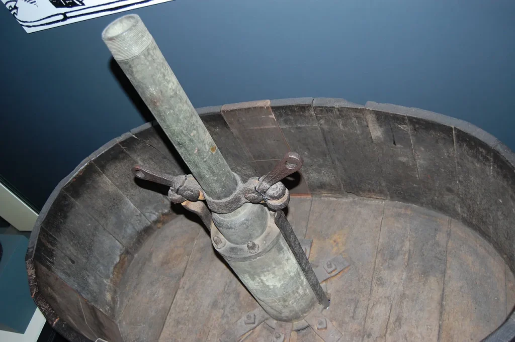 Top-down photograph of a 17th-century wooden fire engine with a large open water tank and internal pump mechanism, displayed at the Museum of London.